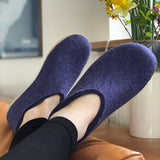 Person wearing purple slippers with a vase of yellow flowers in the background